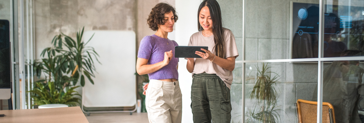 Two woman walking and looking at a laptop on an office