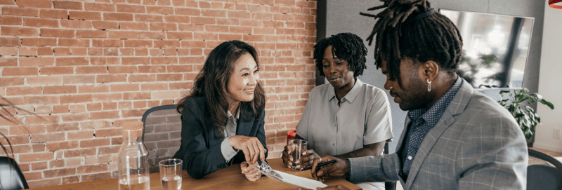 Three people signing paperwork for private equity investment