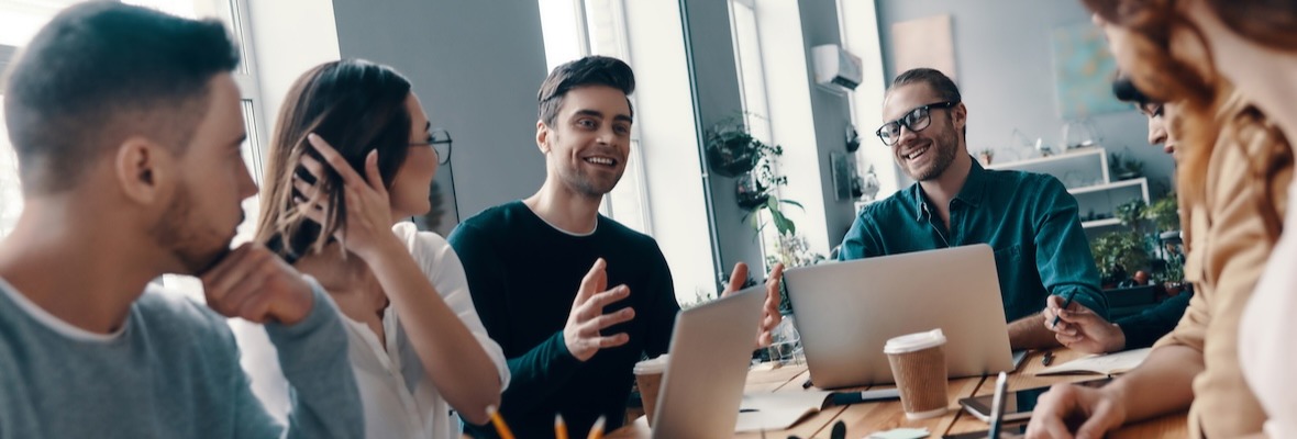 Group of young modern people in smart casual wear discussing something and smiling while working in the creative office