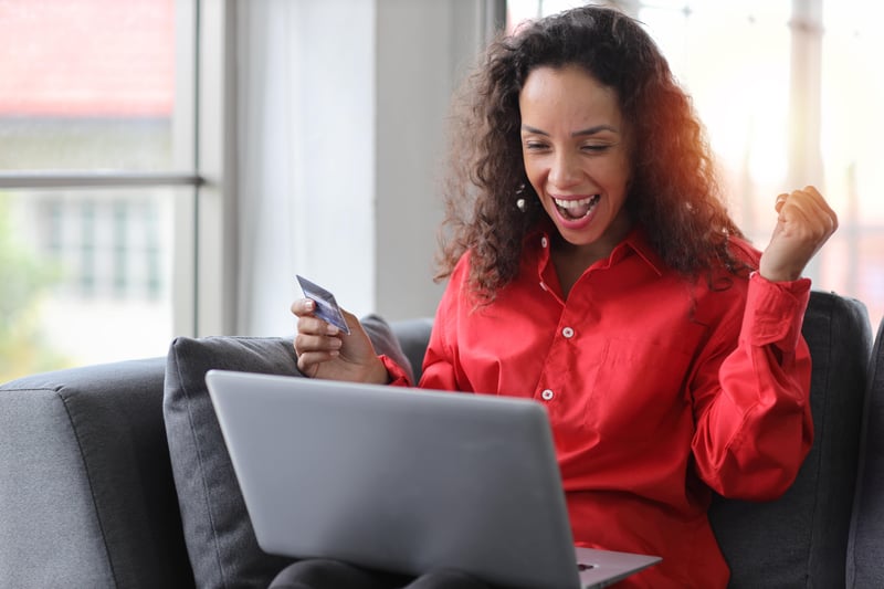 Woman smiling at laptop, happy about BFCM sales 