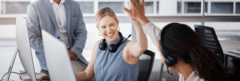 Two female marketers doing a high five while working