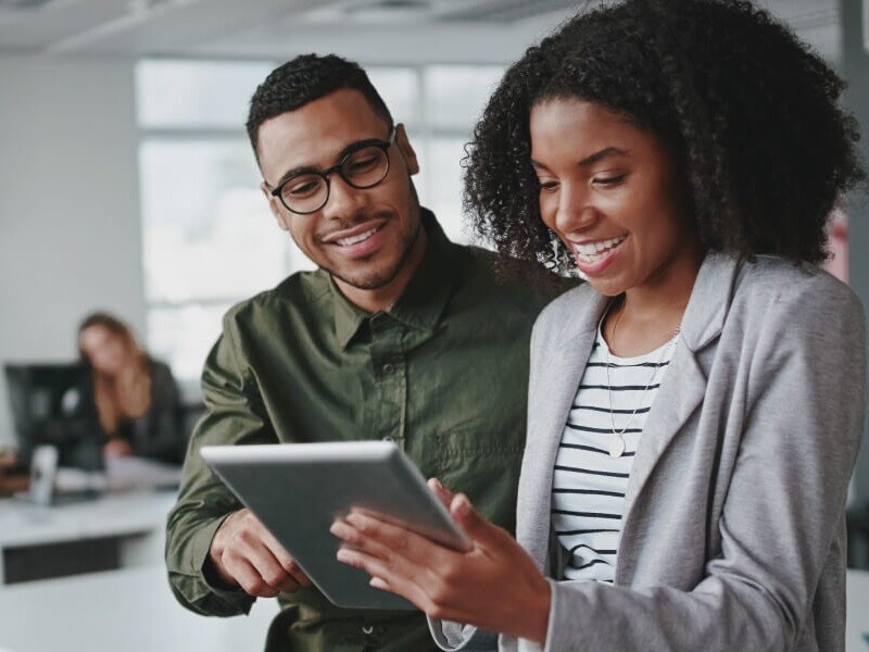 Woman and man looking and smiling at an ipad