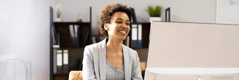 A short haired woman working on a computer while smiling.