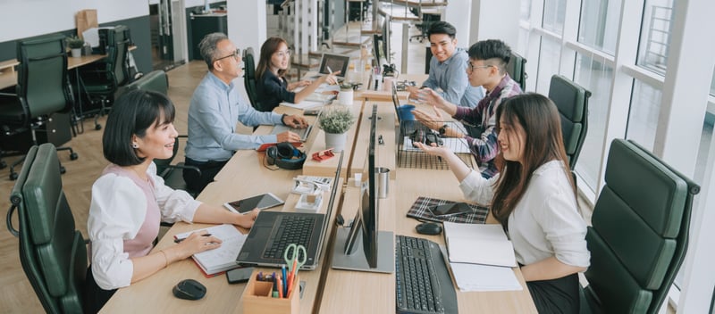 Several people working in a big office table