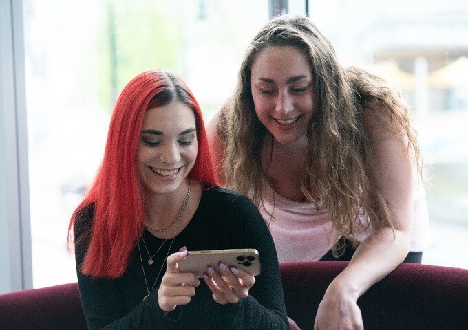 two women looking at a phone and smiling