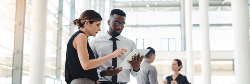 Two marketers standing and looking at a tablet in an office setting