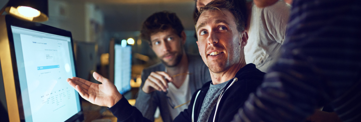 A marketer showing colleagues his work in his computer screen