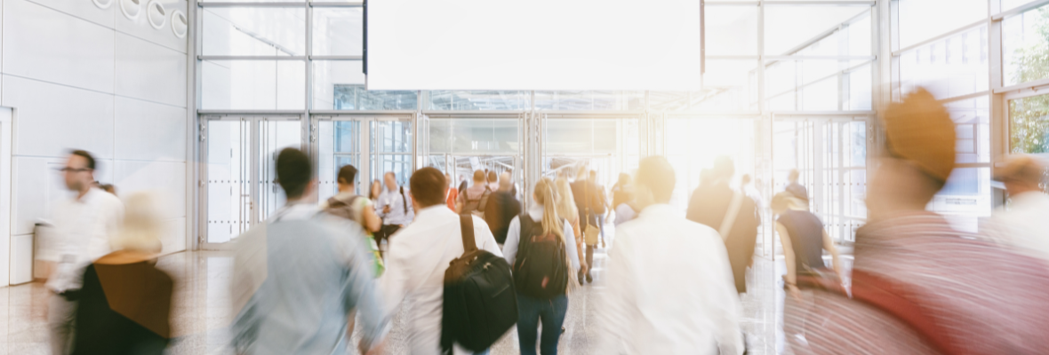 A group of people walking to the entrance of a trade show