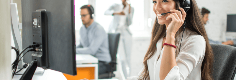 Customer support agent looking at her computer while smiling