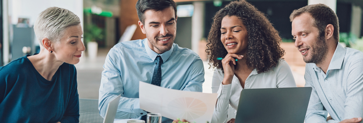 A group of marketers looking at a piece of paper in an office setting while smiling