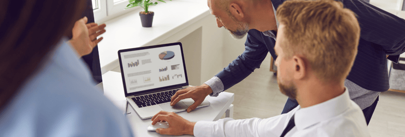 Three marketers analyzing data on a laptop