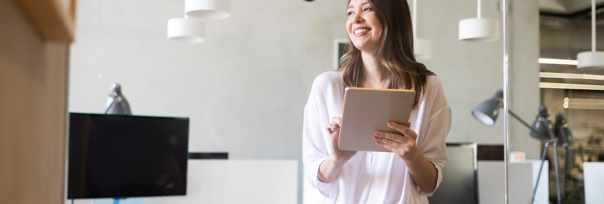 Woman in an office holding a tablet and smiling