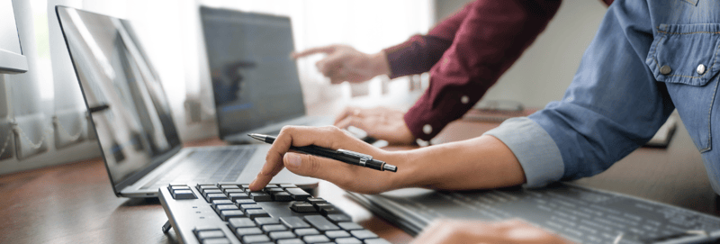 Close up image of two co-workers working together on different computers