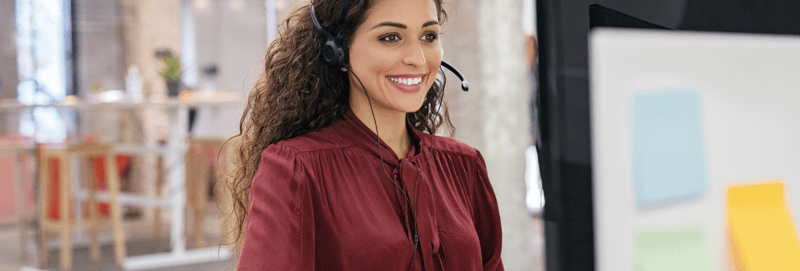 Sales representative sitting in front of a computer while smiling