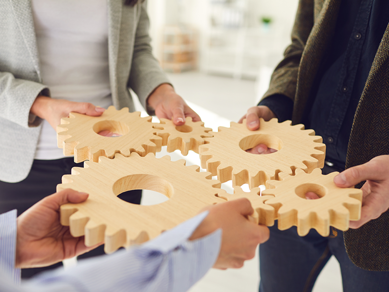 people holding various gears together to create one system