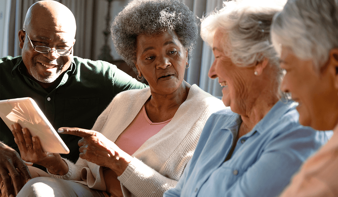 four senior conversing over an tablet