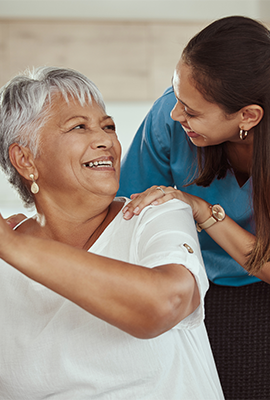 senior woman and senior living assistant smiling at one another